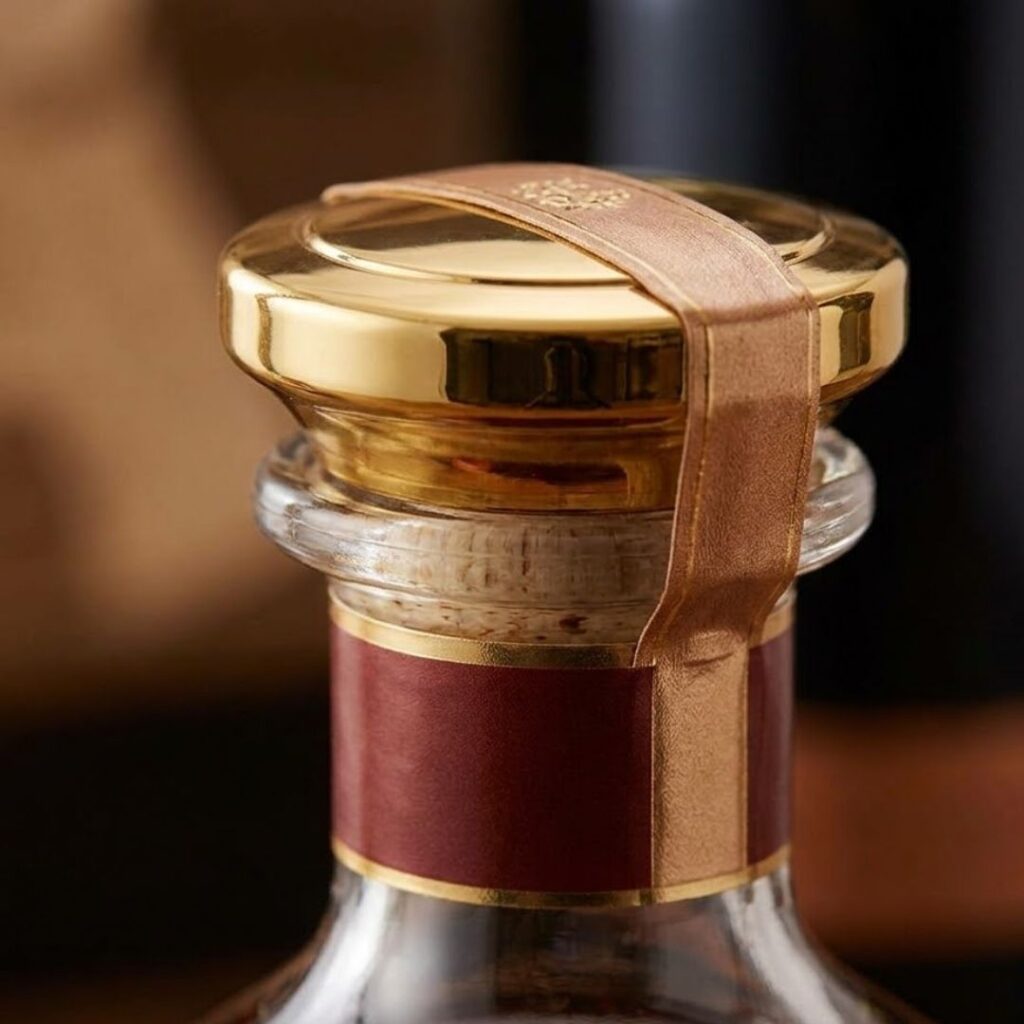 A detailed macro photograph captures a close-up of a high-end, premium metallic closure being perfectly sealed onto a spirit bottle, emphasizing precision.